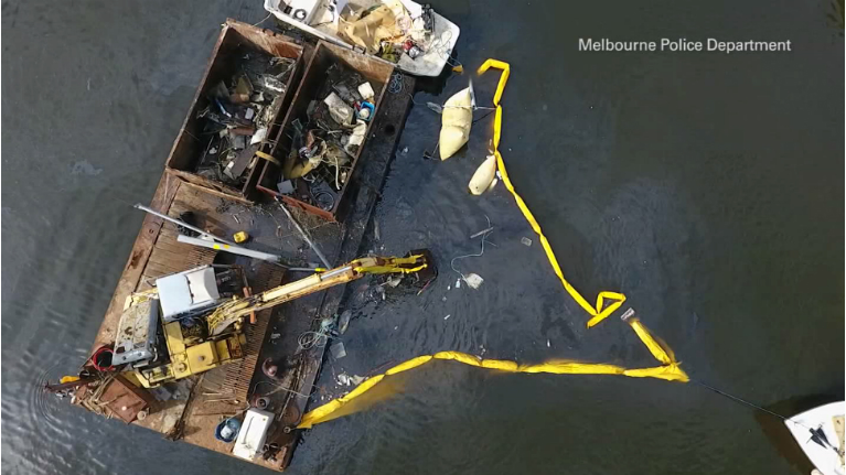 Brevard County workers use a backhoe to dredge the derelict sailboat from the Eau Gallie River last week. The owner of the vessel, if found, could face charges. (Melbourne Police)